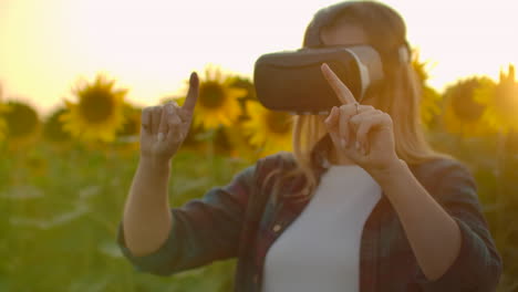 The-female-is-working-in-VR-glasses.-She-is-engaged-in-the-working-process.-It-is-a-perfect-sunny-day-in-the-sunflower-field.